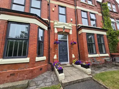 a brick house with a blue door and purple flowers at Victorian Renovation Room 3 in Liverpool