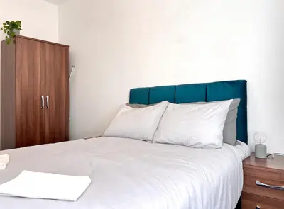 a bed with a blue headboard and white pillows at Spare Property Sasco in Blackpool