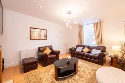 a living room with leather furniture and a table at Chestnut Heritage,- Large & Cheerful 5 bedroom house with free parking in Liverpool