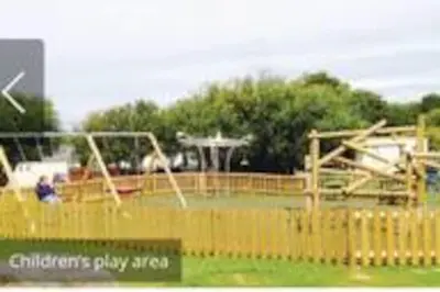 a childrens play area with swings and a playground at Lake View Lodge in Millom