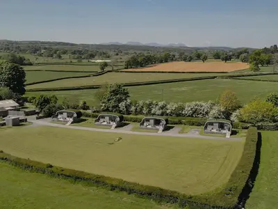 an aerial view of a large green field with domes at Little Heaning in Cartmel