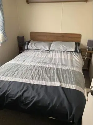 a bedroom with a large bed with a wooden headboard at A family-friendly, eight birth, 2019 Abbey Trieste Caravan in Morecambe