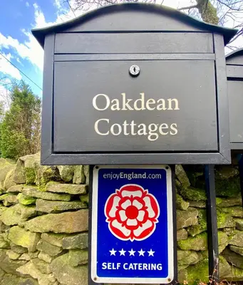 a sign for a caledonian cottages on a stone wall at Hodder Cottage in The Ribble Valley in Whalley