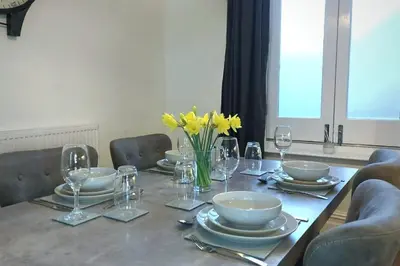 a table with plates and glasses and yellow flowers on it at Stylish Apartment in City Centre with Parking in Preston