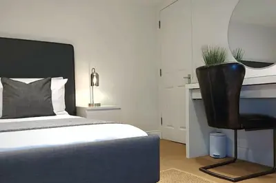 a bedroom with a bed and a black chair at Stylish Apartment in City Centre with Parking in Preston