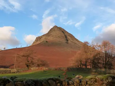 a mountain in the middle of a field with trees at Beech in Ulverston