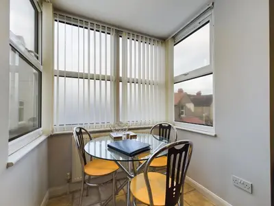 a dining room with a table and chairs and windows at Sunrise Suite in Blackpool