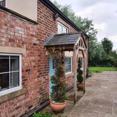 a brick house with an awning and two potted plants at The Coach House in Blackpool