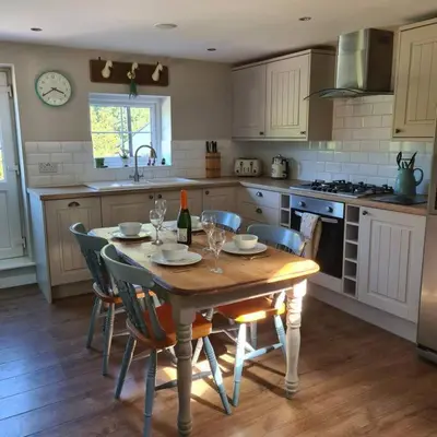 a kitchen with a wooden table with chairs and a table and a table at The Coach House in Blackpool